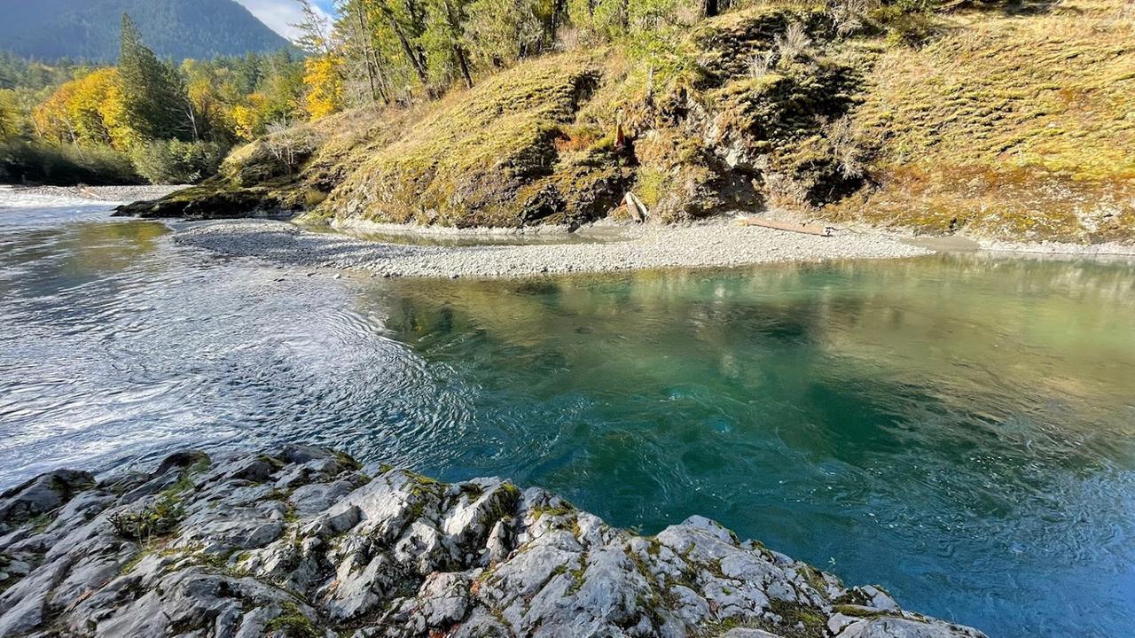Ein blauschimmernder Fluß zwischen Felsblöcken und inmitten einer grünen Berglandschaft. Ein blauschimmernder Fluß zwischen Felsblöcken und inmitten einer grünen Berglandschaft.