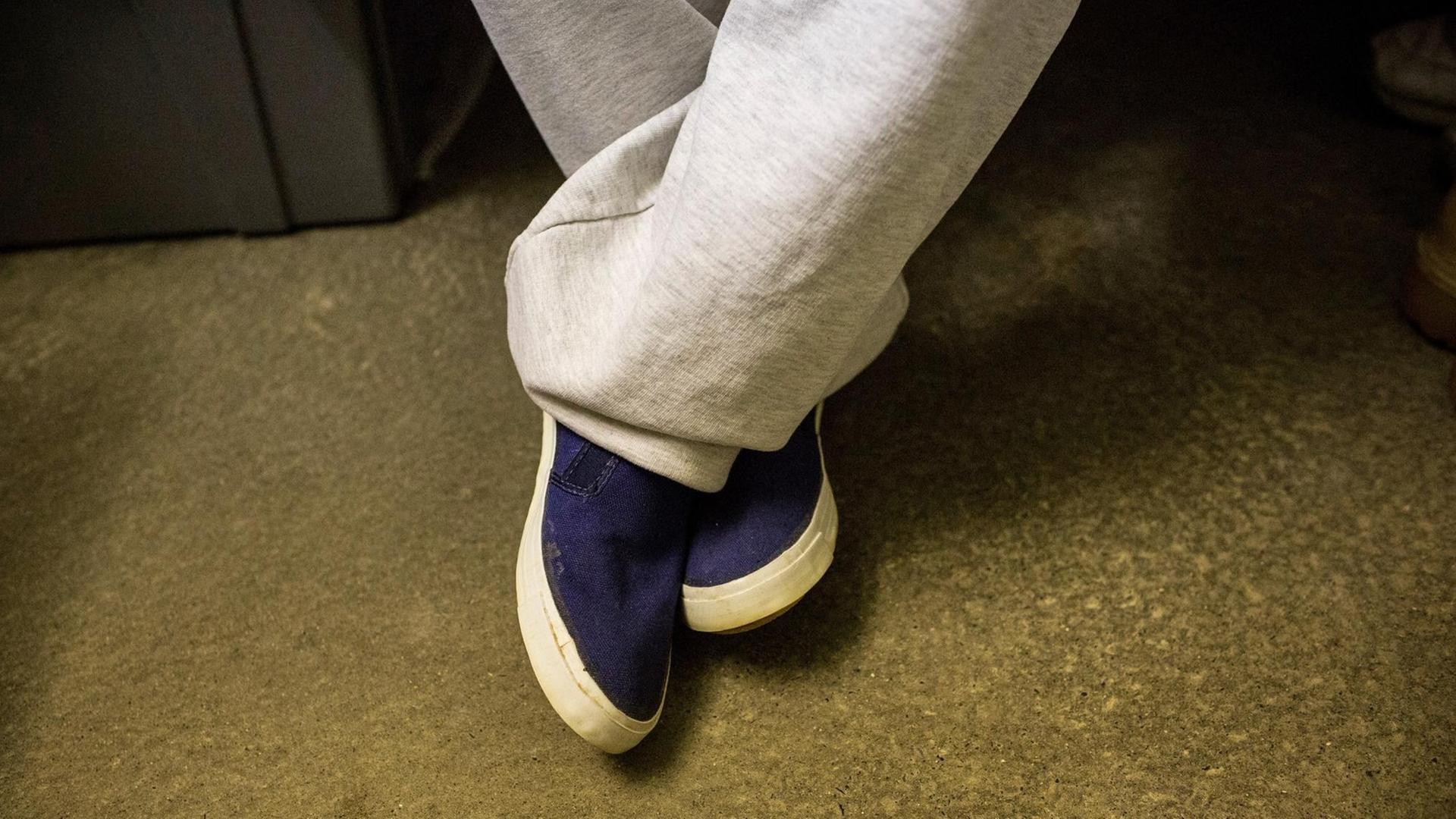 Nahaufnahme der Beine und Schuhe eines Gefangenen in seiner Zelle. Nahaufnahme der Beine und Schuhe eines Gefangenen in seiner Zelle.