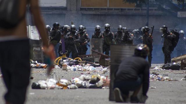 Sicherheitskräfte bewachen am 20.07.2017 eine von Demonstranten blockierte Straße in Caracas (Venezuela). Viele Läden und Geschäfte der Hauptstadt blieben angesichts des eines Generalstreiks geschlossen. Aufgerufen wurde der Streik von der Opposition. Ihr Ziel: die von Präsidenten Maduro geplante Verfassungsreform zu verhindern. Straßen wurden von Demonstranten blockiert. Foto: Rayner Pena/dpa | Verwendung weltweit
