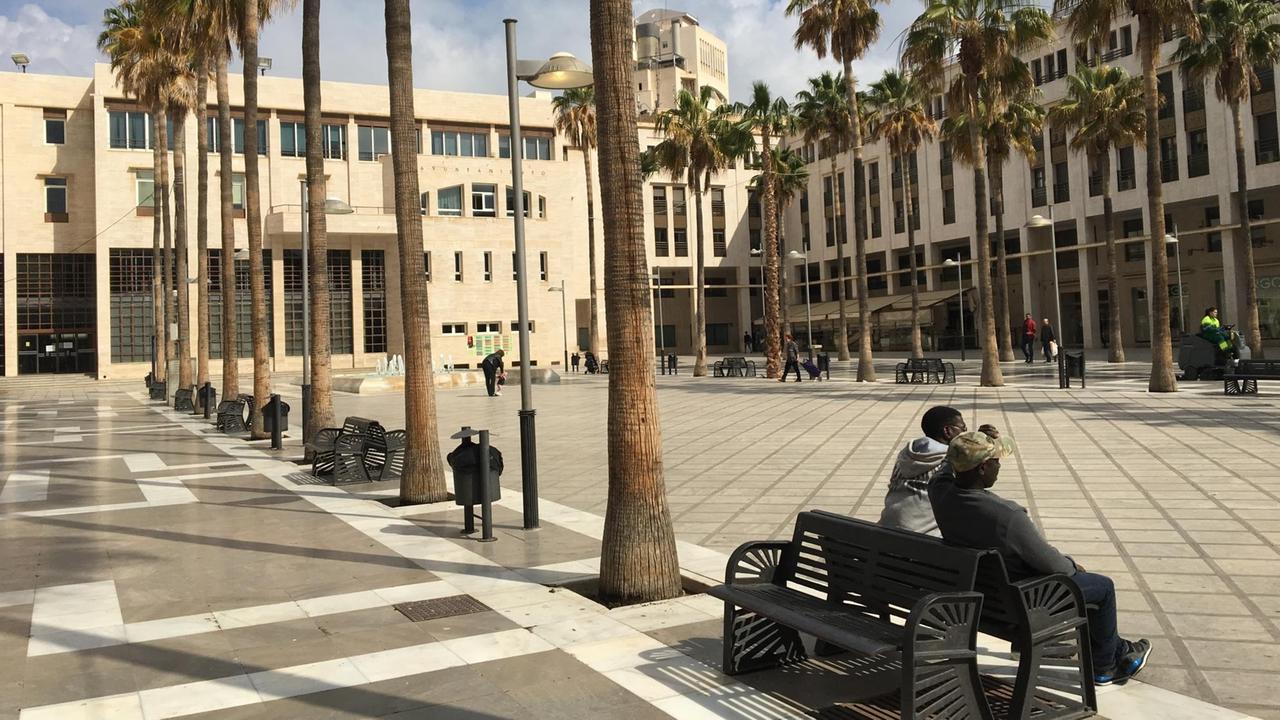 Der Rathausplatz von El Ejido, auf einer Bank sitzen zwei Menschen dunkler Hautfarbe. Der Rathausplatz von El Ejido, auf einer Bank sitzen zwei Menschen dunkler Hautfarbe.