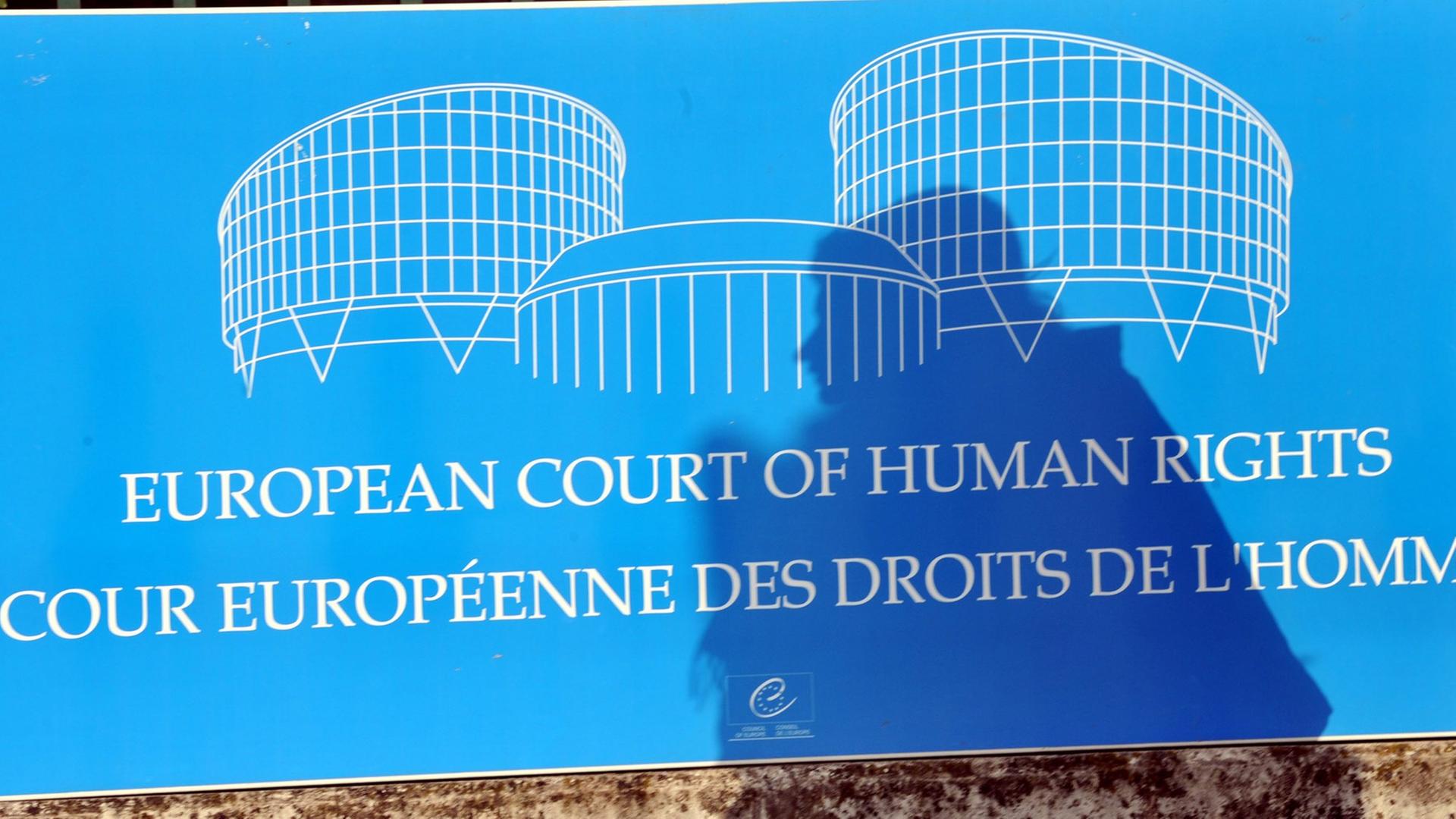 Der Schatten einer Frau fällt auf ein Schild vor dem Gebäude des Europäischen Gerichtshofs für Menschenrechte (EGMR) in Straßburg.
