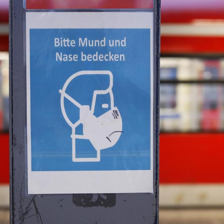 Ein Hinweisschild weist die Fahrgäste am Bahnhof Köln Deutz / Messe auf die wegen der Coronaschutzverordnung geltenden Corona-Maßnahmen hin wie das Tragen von Masken in Bus und Bahn.
