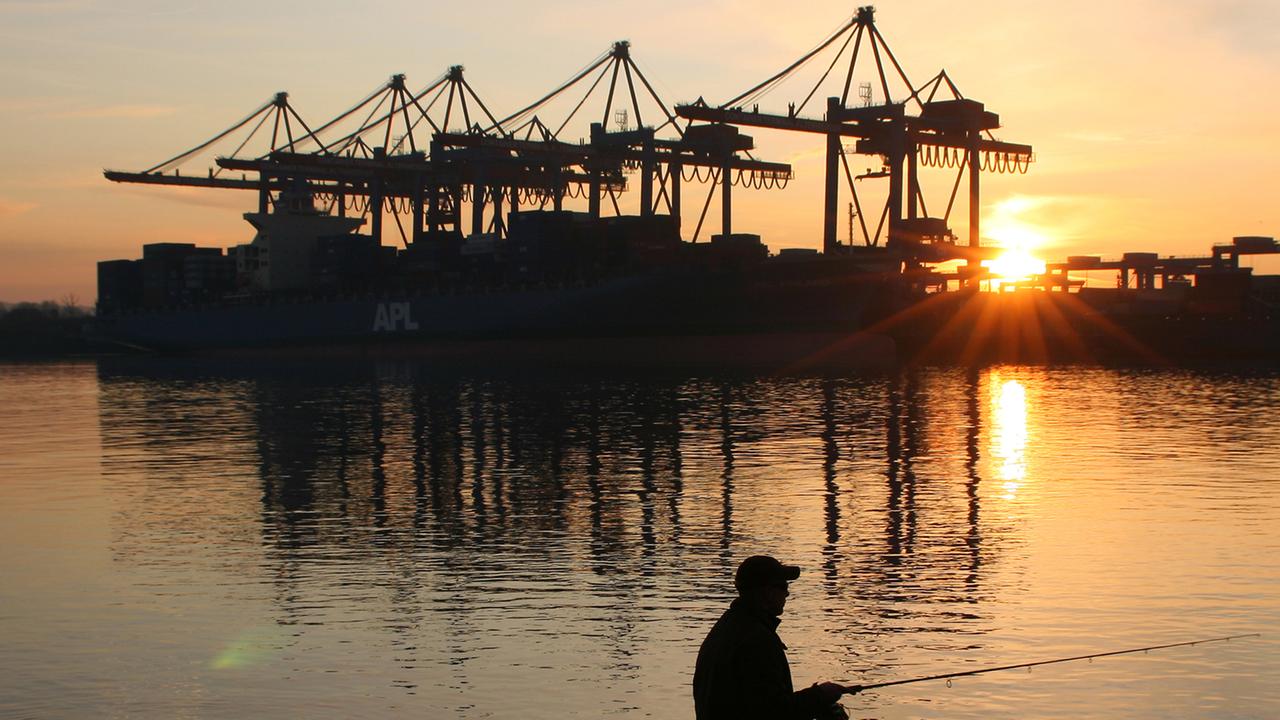Ein Mann angelt am während des Sonnenuntergangs vor dem Container-Terminal Altenwerder (CTA) im Hamburger Hafen. Ein Mann angelt am während des Sonnenuntergangs vor dem Container-Terminal Altenwerder (CTA) im Hamburger Hafen.