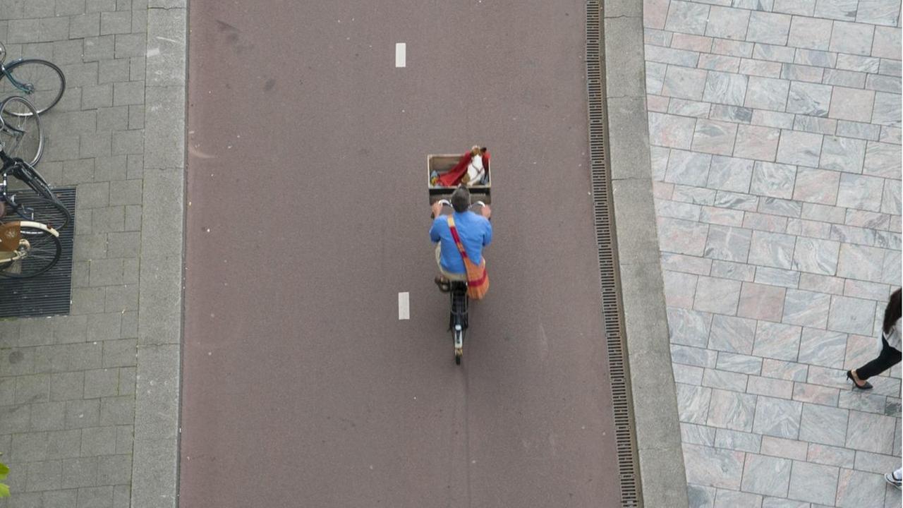Ein Radfahrer wird aus der Vogelperspektive auf einem gut ausgebauten, rot geteerten Radweg gezeigt. Ein Radfahrer wird aus der Vogelperspektive auf einem gut ausgebauten, rot geteerten Radweg gezeigt.