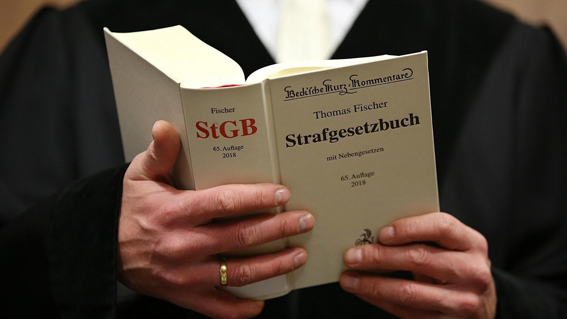 Ein Richter am Oberlandesgericht in Köln mit dem Strafgesetzbuch (StGB) in der Hand. Foto: Oliver Berg/dpa | Verwendung weltweit