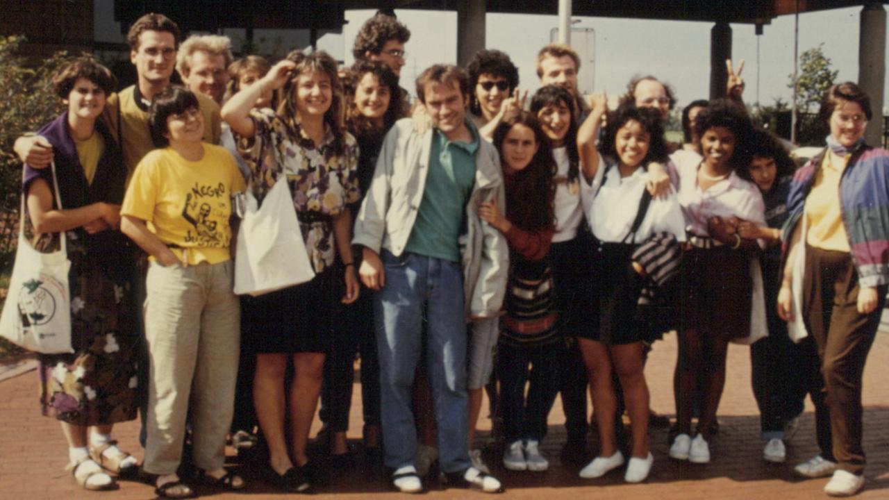 Junge Leute in typischer Kleidung der 80er Jahre stehen in einer Gruppe zusammen und blicken in die Kamera. Junge Leute in typischer Kleidung der 80er Jahre stehen in einer Gruppe zusammen und blicken in die Kamera.