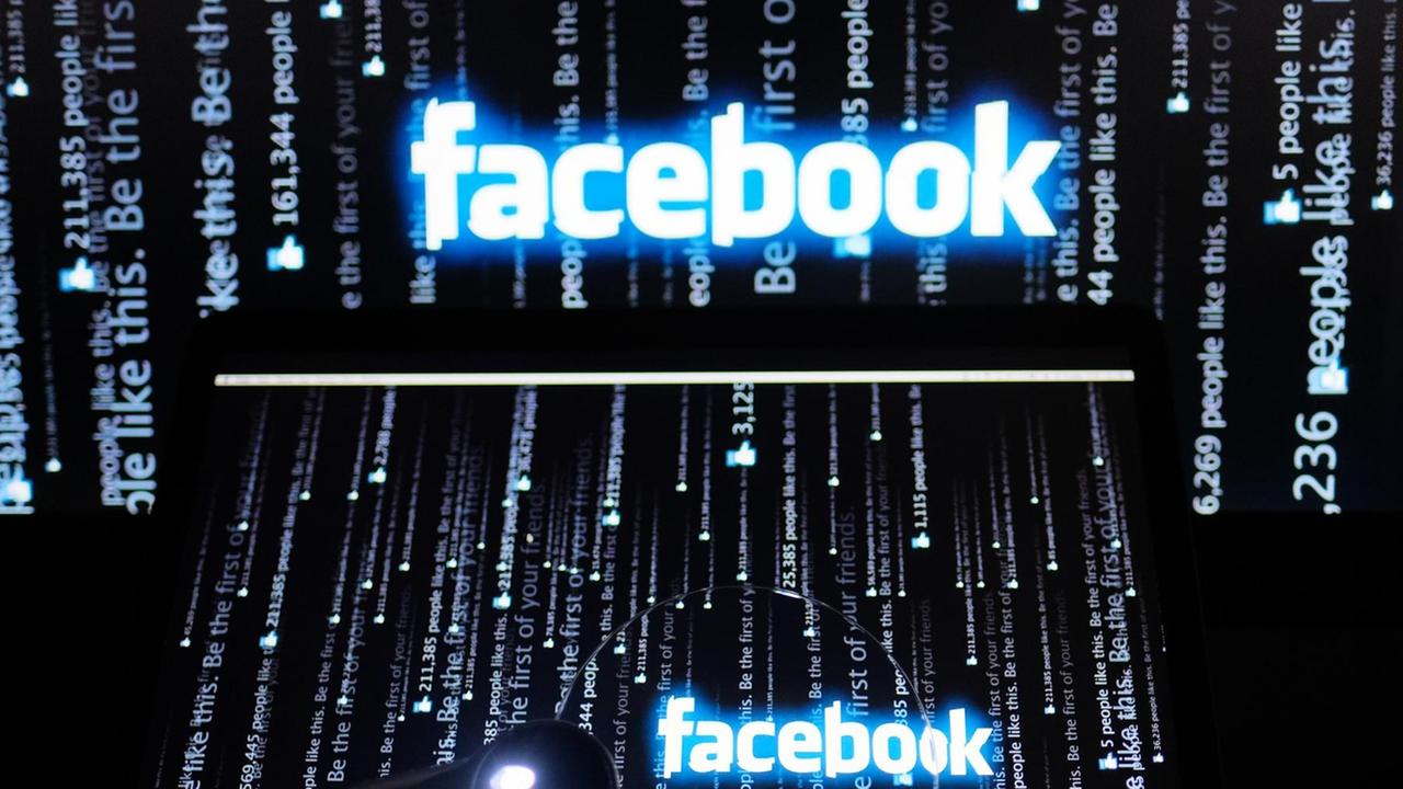 Der weiße Facebook-Schriftzug mit blauem Rand leuchtet auf einem schwarzen Bildschirm, auf dem weiße Schriftzeilen senkrecht von unten nach oben verlaufen.