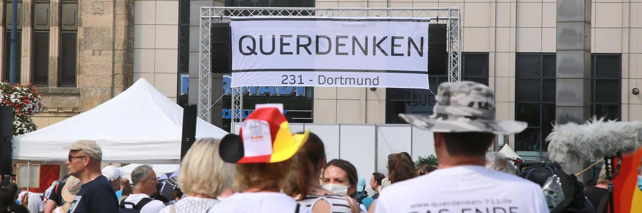 Demonstration gegen die staatlichen Corona-Schutzmaßnahmen am 9.08.2020 in Dortmund. Über den Menschen ist ein Plakat mit der Aufschrift "Querdenken" angebracht.