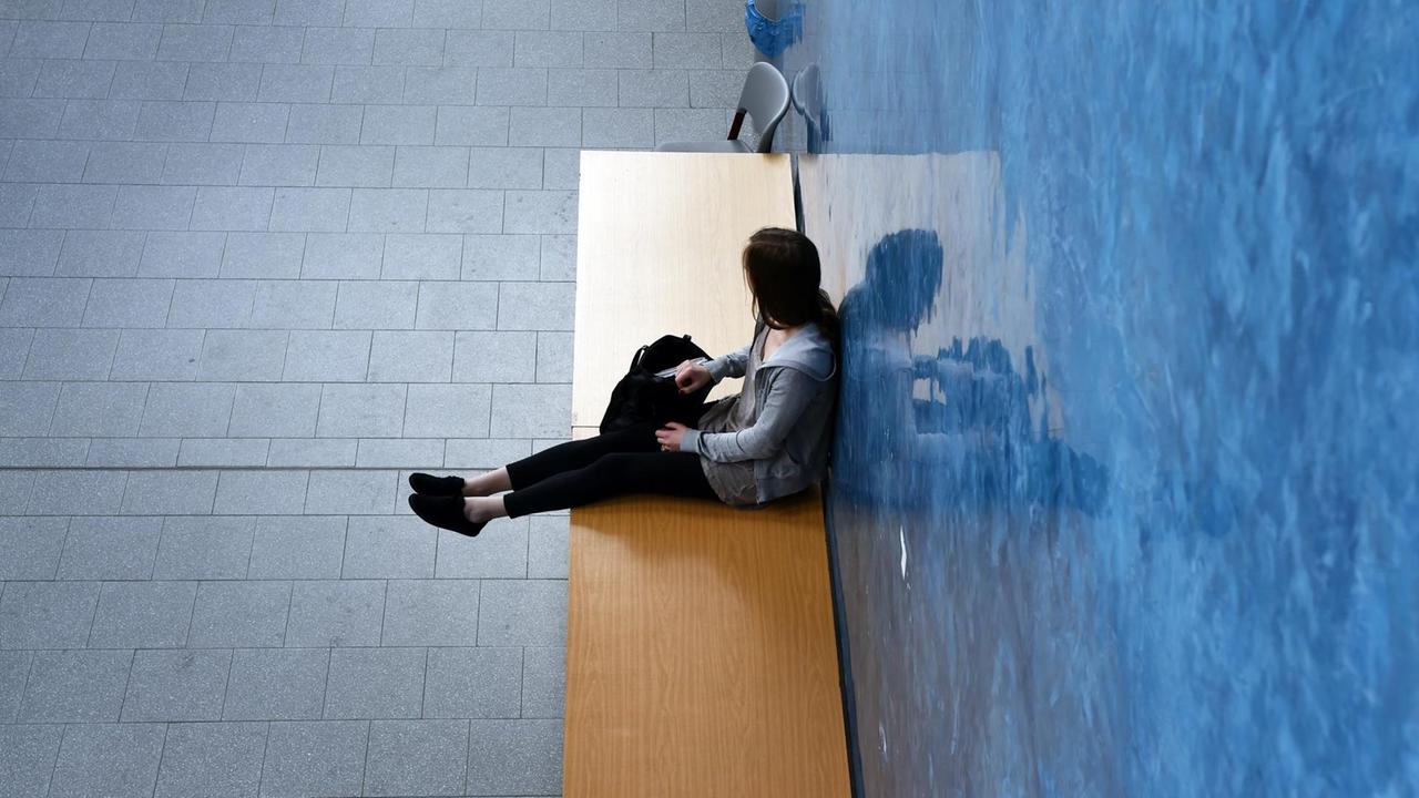 Eine junge Frau sitzt am 03.07.2014 in Potsdam auf einer Bank. Foto: Jens Kalaene | Verwendung weltweit Eine junge Frau sitzt am 03.07.2014 in Potsdam auf einer Bank. Foto: Jens Kalaene | Verwendung weltweit