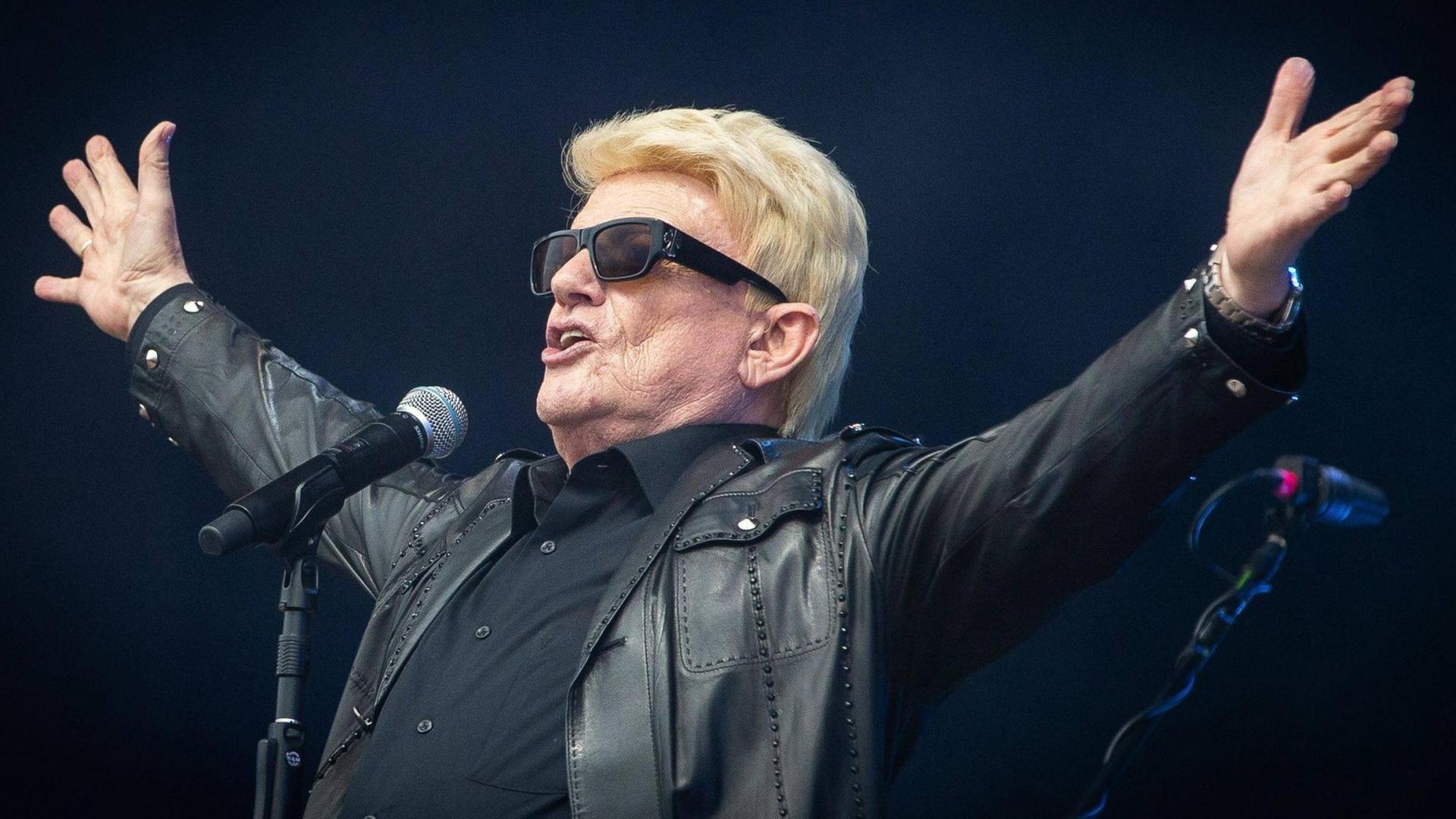 Heino ist in schwarz gekleidet, trägt eine schwarze Sonnenbrille und breitet beide Arme aus. Heino ist in schwarz gekleidet, trägt eine schwarze Sonnenbrille und breitet beide Arme aus.