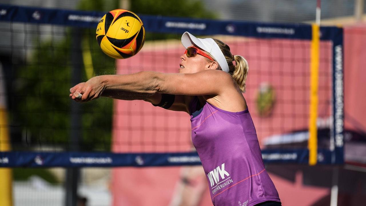 Eine Frau spielt vor einem Netz einen Volleyball. Eine Frau spielt vor einem Netz einen Volleyball.