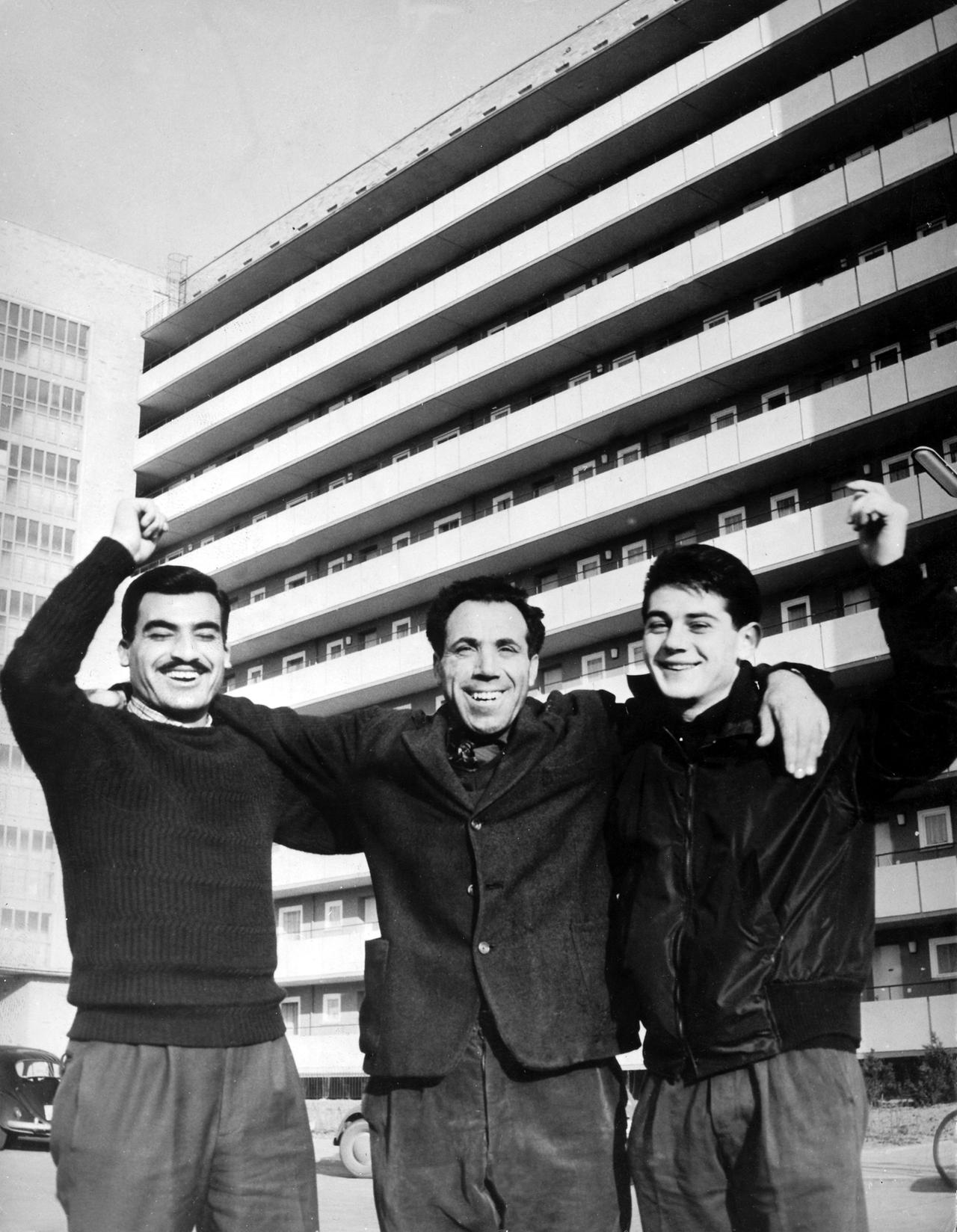 Lächelnd stehen drei italienische Gastarbeiter 1961 vor einem modernen Junggesellenheim in Braunschweig. Sie bewohnen dort ein Zimmer im 11. Stock. In dem Wohnblock stehen rund 250 Betten für alleinstehende, ausländische Arbeitnehmer zur Verfügung. Die Zimmer, die mit ein bis drei Mann belegt werden, liegen im 9. bis 11. Stockwerk und kosten inklusive Heizung und Wäsche zwischen 55 und 62 Mark. Lächelnd stehen drei italienische Gastarbeiter 1961 vor einem modernen Junggesellenheim in Braunschweig. Sie bewohnen dort ein Zimmer im 11. Stock. In dem Wohnblock stehen rund 250 Betten für alleinstehende, ausländische Arbeitnehmer zur Verfügung. Die Zimmer, die mit ein bis drei Mann belegt werden, liegen im 9. bis 11. Stockwerk und kosten inklusive Heizung und Wäsche zwischen 55 und 62 Mark.