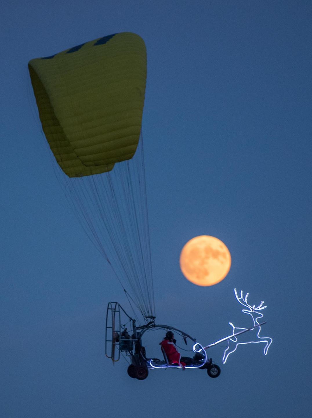 Im Trike und Motorgleitschirm fliegt am 02.12.2017 ein Mann im Weihnachtsmannkostüm und beleuchtetem Rentier über die Landschaft mit dem zunehmenden Mond nahe Sieversdorf (Brandenburg). Foto: Patrick Pleul/dpa-Zentralbild/dpa | Verwendung weltweit Im Trike und Motorgleitschirm fliegt am 02.12.2017 ein Mann im Weihnachtsmannkostüm und beleuchtetem Rentier über die Landschaft mit dem zunehmenden Mond nahe Sieversdorf (Brandenburg). Foto: Patrick Pleul/dpa-Zentralbild/dpa | Verwendung weltweit
