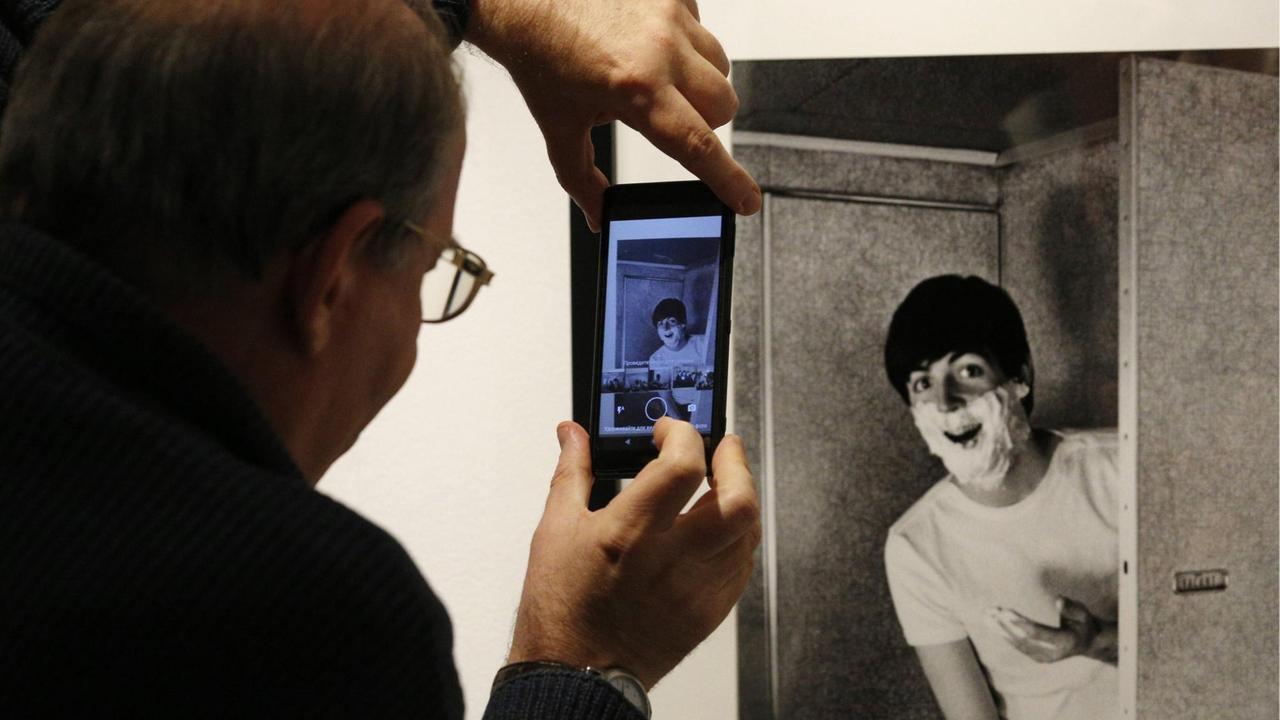 Ein Besucher fotografiert ein Bild Paul McCartneys auf einer Ausstellung des Fotografen Harry Benson in Moskau.