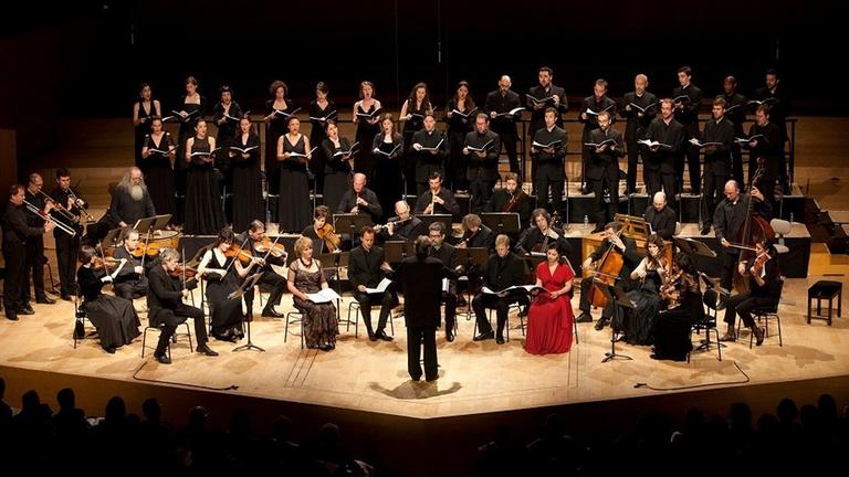 Ein Chor steht hinter einem Orchester mit alten Instrumenten. Ein Chor steht hinter einem Orchester mit alten Instrumenten.