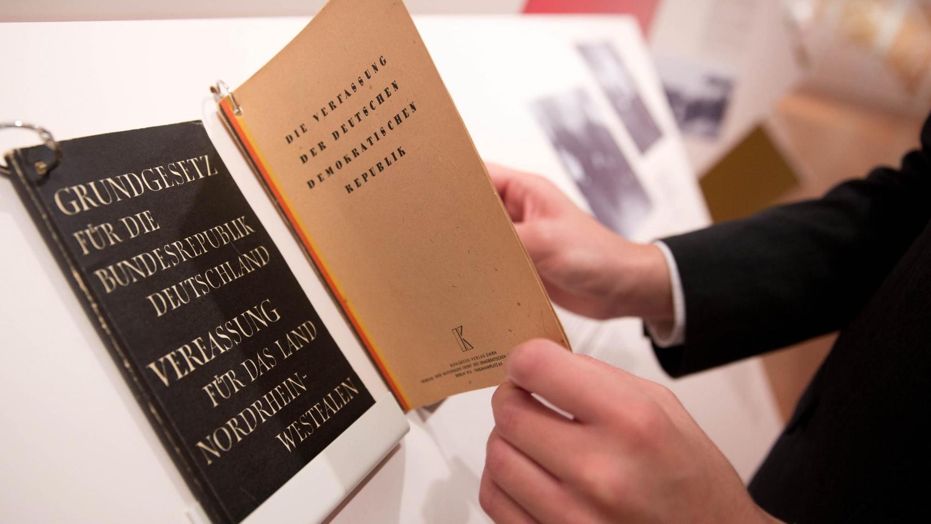 Ein Besucher blättert am 28.10.2015 im Martin-Gropius-Bau in Berlin in der Ausstellung «Russland und Deutschland. Von der Konfrontation zur Zusammenarbeit» neben dem Grundgesetz der Bundesrepublik Deutschland in einer Verfassung der DDR. Ein Besucher blättert am 28.10.2015 im Martin-Gropius-Bau in Berlin in der Ausstellung «Russland und Deutschland. Von der Konfrontation zur Zusammenarbeit» neben dem Grundgesetz der Bundesrepublik Deutschland in einer Verfassung der DDR.