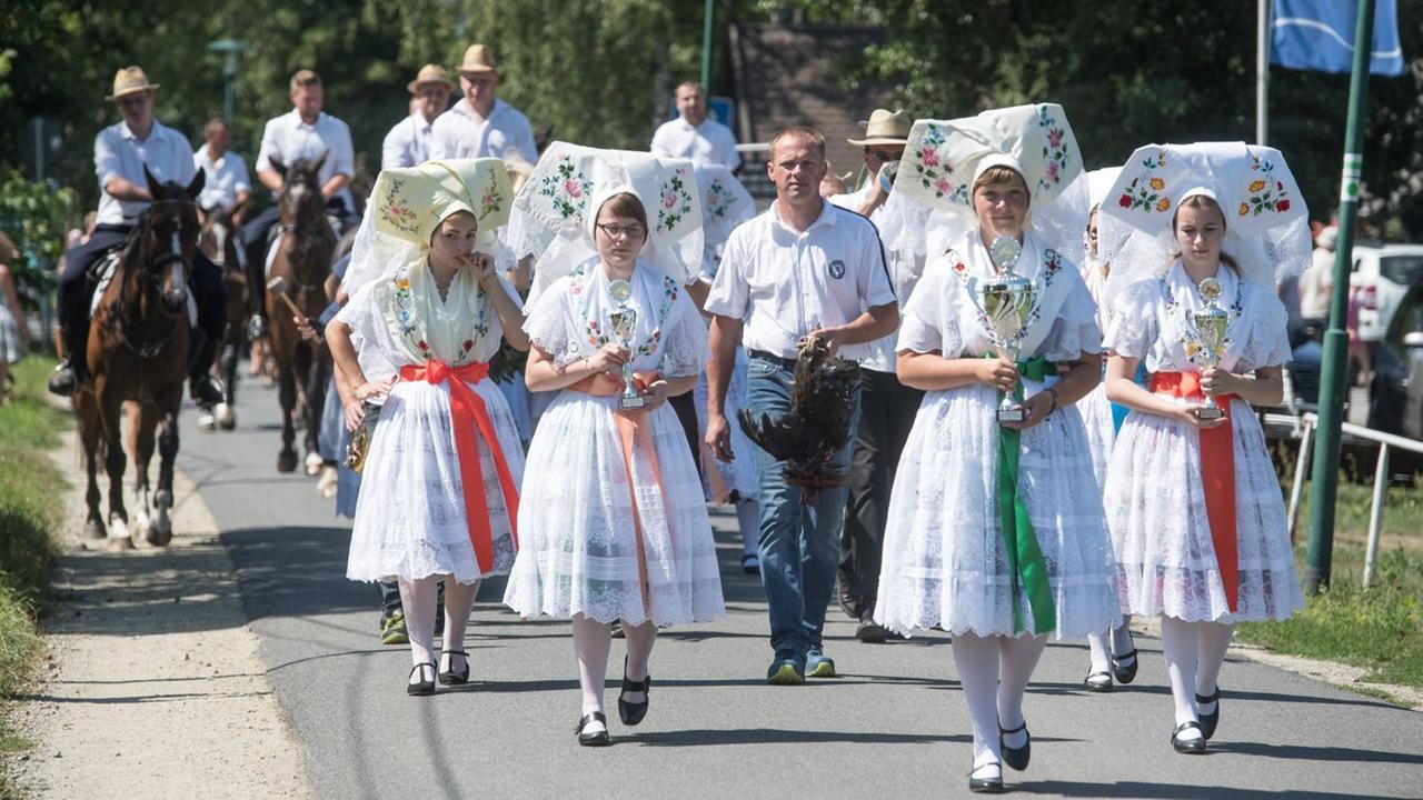 Junge Frauen und Männer in sorbischer Tracht nehmen im Spreewald am traditionellen Hahnrupfen teil. Junge Frauen und Männer in sorbischer Tracht nehmen im Spreewald am traditionellen Hahnrupfen teil.