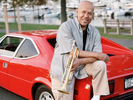 Der Jazz-Trompeter Eddie Henderson lehnt amn einem roten Sportwagen.