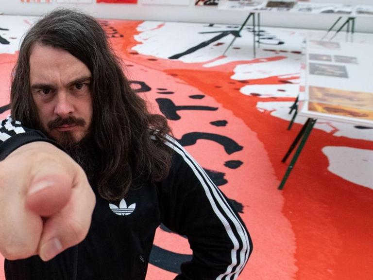 Jonathan Meese, Maler und Aktionskünstler, steht bei einem Interviewtermin in dem noch geschlossenen Ausstellungsraum der Ausstellung "Die Irrfahrten des Meese". Die Ausstellung in der Neuen Pinakothek, welche Werke aus 25 Jahren zeigt.