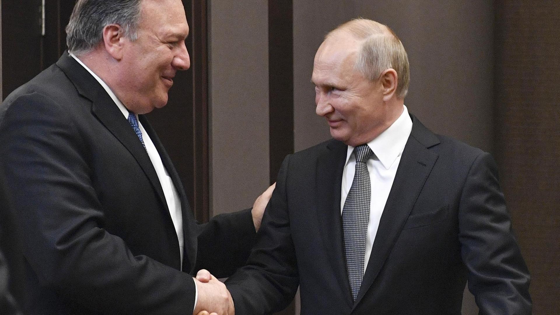 Mike Pompeo und Wladimir Putin begrüßen sich mit Handschlag. Beide machen ein freundliches Gesicht. Mike Pompeo und Wladimir Putin begrüßen sich mit Handschlag. Beide machen ein freundliches Gesicht.