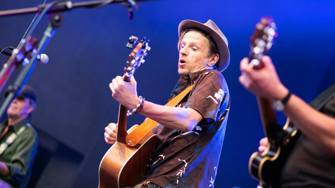 Schauspieler Alexander Scheer spielt auf der Bühne Gitarre und singt. Schauspieler Alexander Scheer spielt auf der Bühne Gitarre und singt.