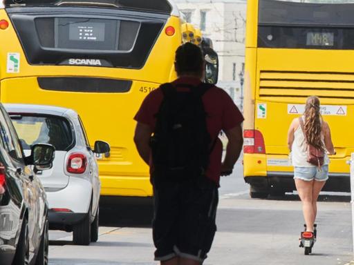 29.07.2019, Berlin: Zwei E-Scooter Fahrer fahren auf dem Fahrradweg an der Karl-Liebknecht Straße hinter einem BVG-Bus