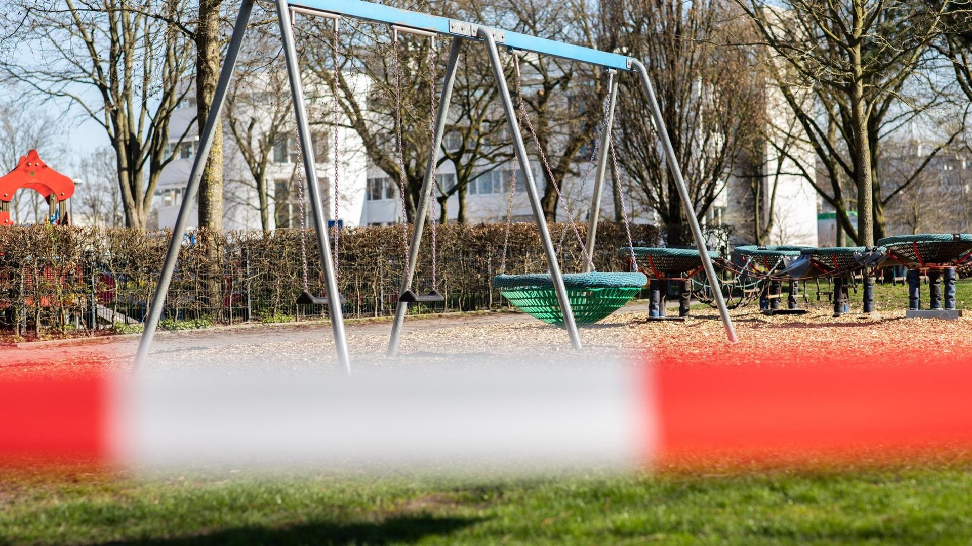 Vor einem Spielplatz ist ein rot-weißes Absperrband gespannt Vor einem Spielplatz ist ein rot-weißes Absperrband gespannt