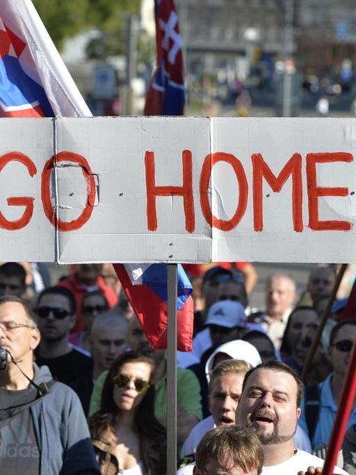 Teilnehmer einer Demonstration gegen Flüchtlinge in der slowakischen Hauptstadt Bratislava halten Flaggen und ein Banner mit der Aufschrift "Go Home" hoch.