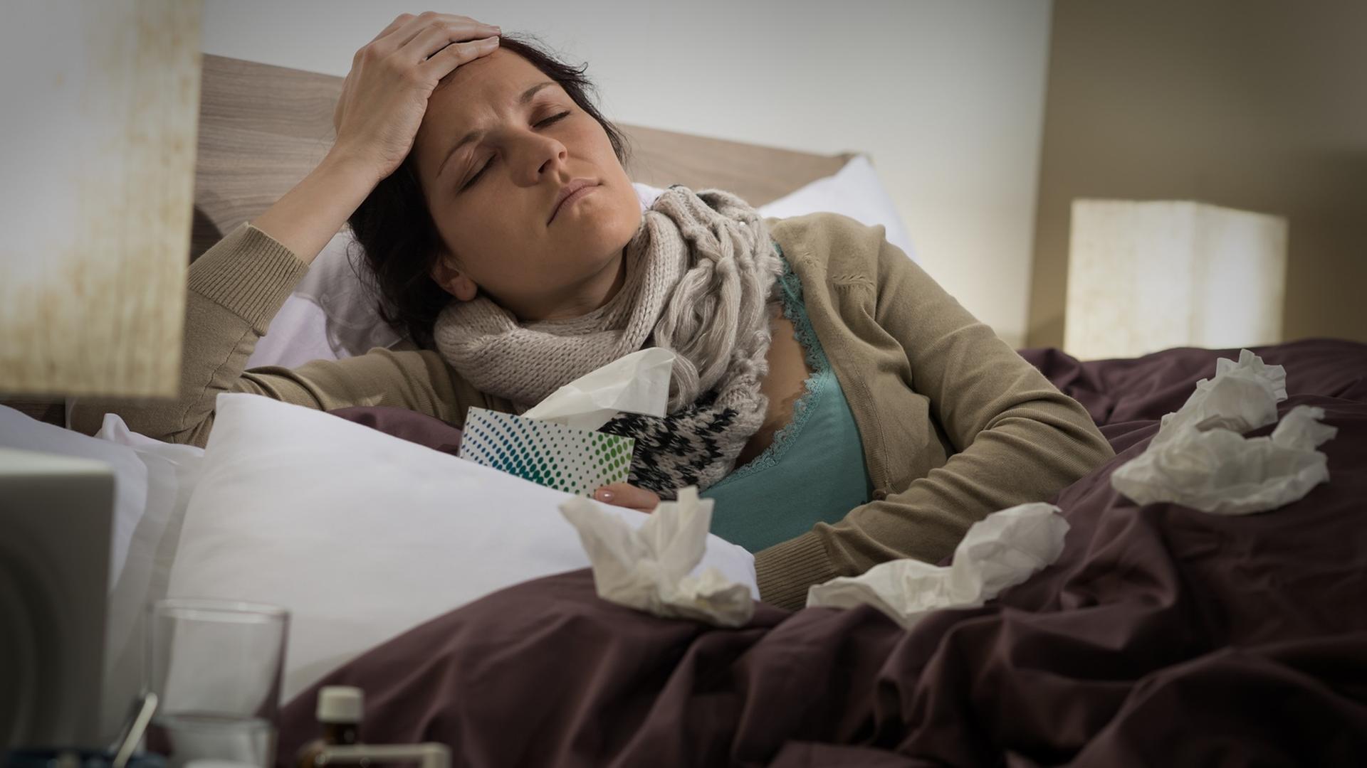 Eine Frau liegt krank im Bett. Eine Frau liegt krank im Bett.