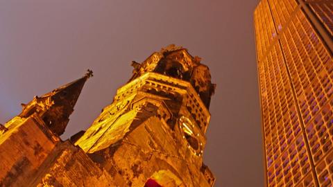 Der neue wie der historische Turm der Kaiser-Wilhelm-Gedächtnis-Kirche wird nachts strahlend illuminiert.