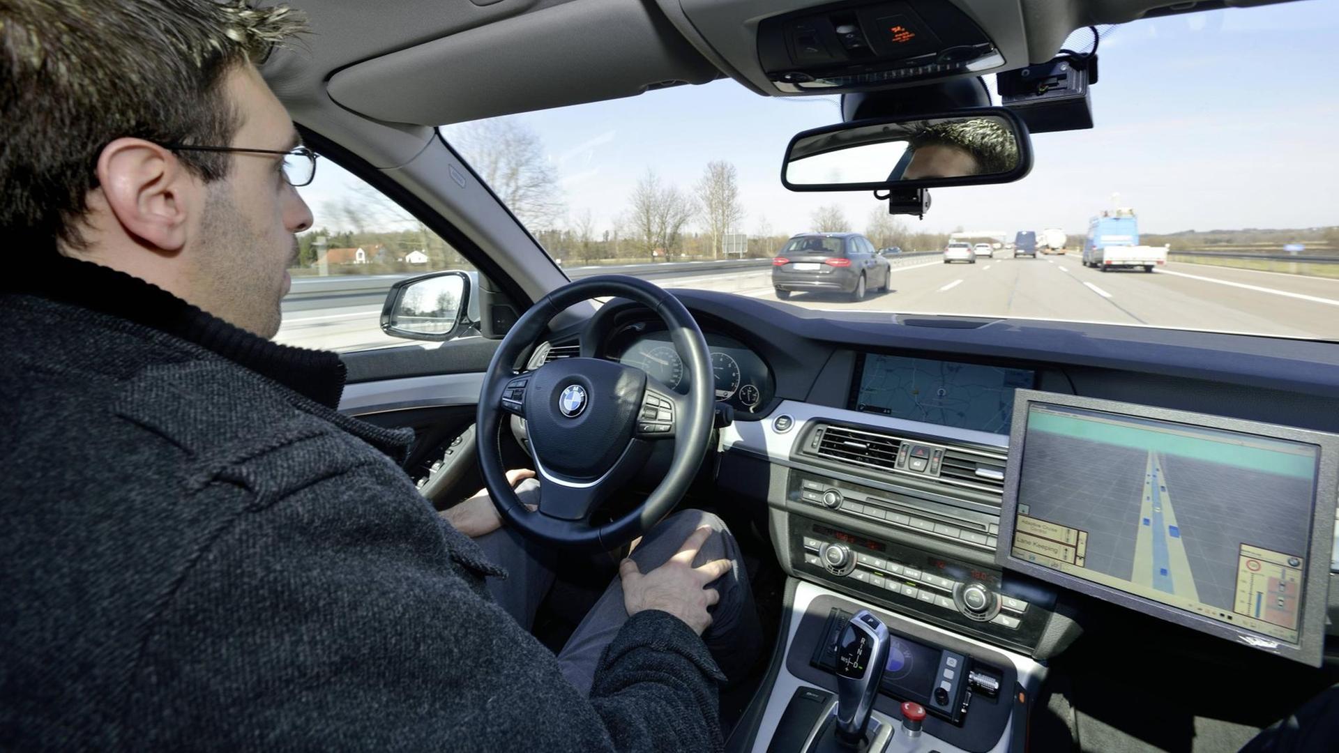 Ein Mann sitzt auf dem Fahrersitz eines Autos, das vom Bordcomputer gesteuert wird Ein Mann sitzt auf dem Fahrersitz eines Autos, das vom Bordcomputer gesteuert wird