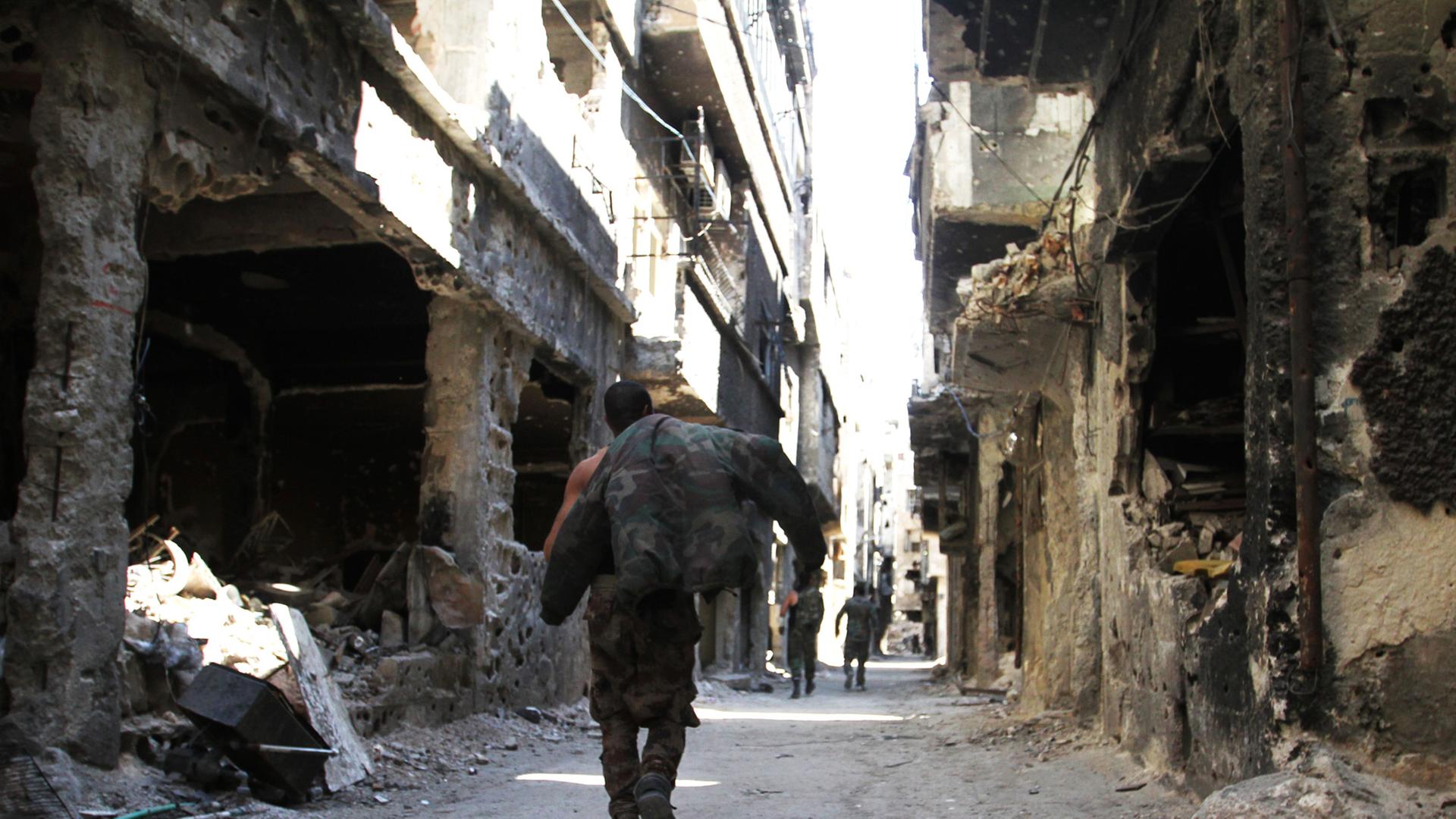 Ein Mann läuft durch eine Straße im zerstörten Flüchtlingsviertel Jarmuk in Damaskus.