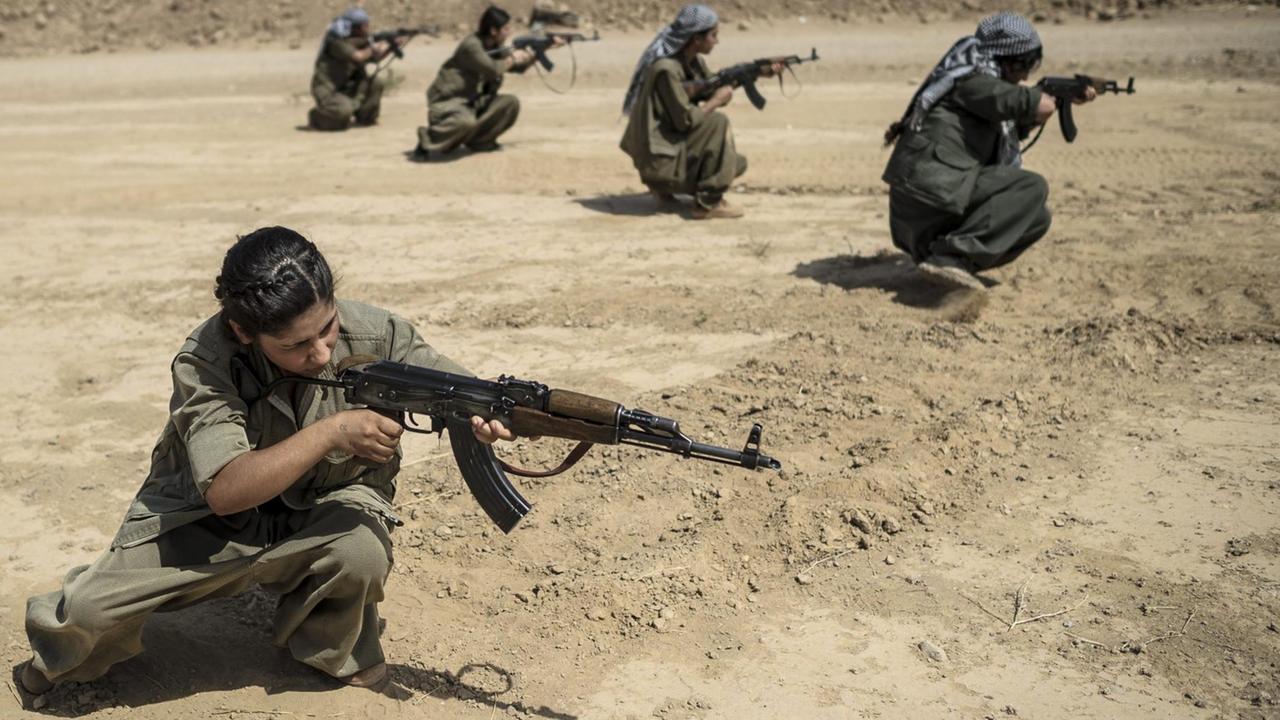 PKK-Kämpferin mit Gewehr im Anschlag kniet auf dem Boden. PKK-Kämpferin mit Gewehr im Anschlag kniet auf dem Boden.