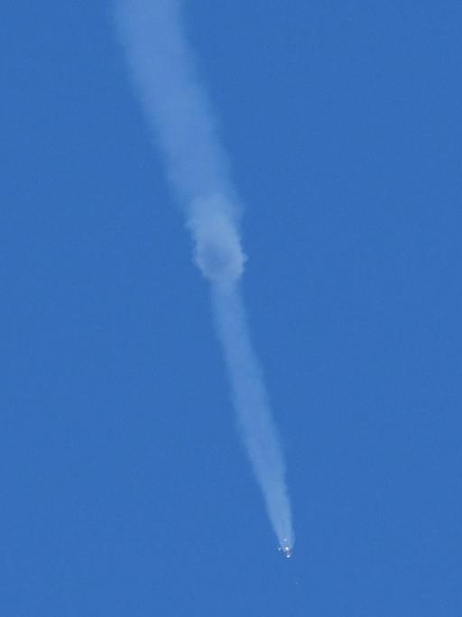 Vor blauem Himmel ist mit einem Schweif aus weißem Rauch die Notlandung der Sojus-Raumkapsel zu sehen.