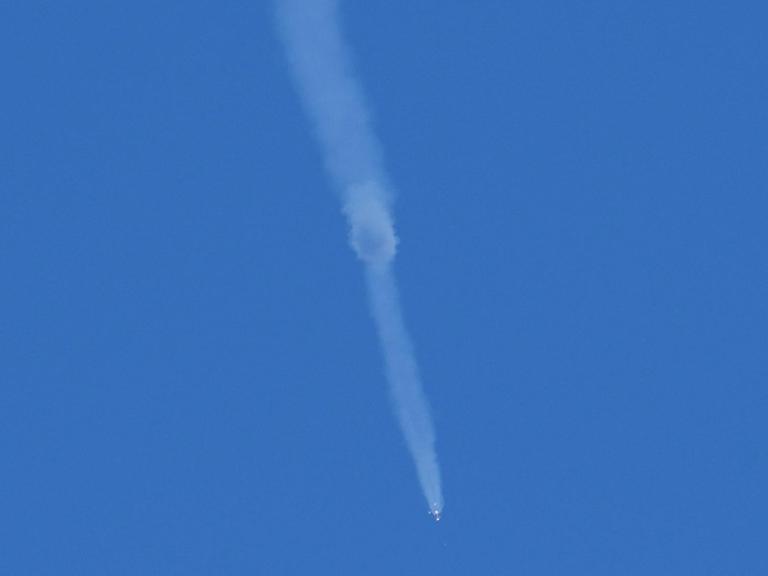 Vor blauem Himmel ist mit einem Schweif aus weißem Rauch die Notlandung der Sojus-Raumkapsel zu sehen.