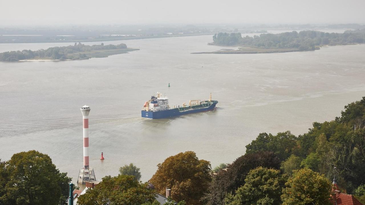 Das Tankschiff Mergus fährt auf der Elbe zwischen dem Leuchtturm Blankenese und den Inseln "Schweinsand" des Naturschutzgebiets Neßsand flussabwärts.