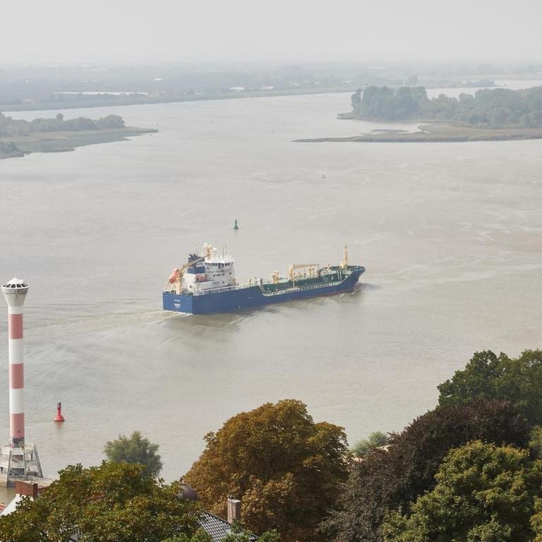 Das Tankschiff Mergus fährt auf der Elbe zwischen dem Leuchtturm Blankenese und den Inseln "Schweinsand" des Naturschutzgebiets Neßsand flussabwärts.