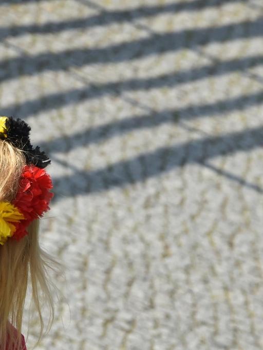 Eine junge Frau kommt mit einem Haarkranz mit schwarz-rot-goldenen Blüten am 15.07.2014 in Berlin zum Empfang der Fußball-Nationalmannschaft.