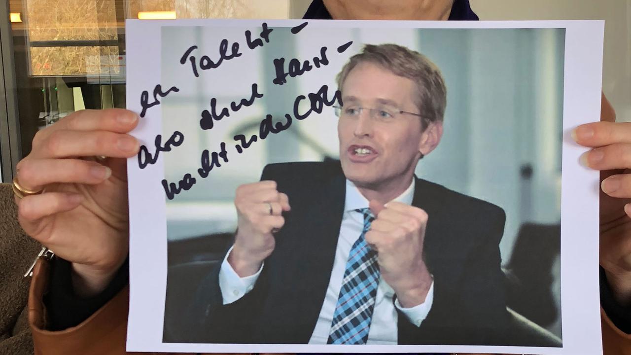 Margaret Heckel hält ein Bild von Daniel Günther hoch, auf das sie etwas geschrieben hat. Margaret Heckel hält ein Bild von Daniel Günther hoch, auf das sie etwas geschrieben hat.