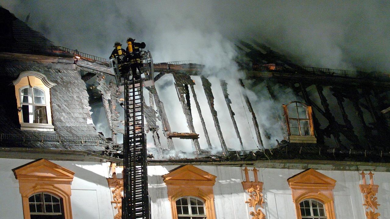 Rauch steigt aus dem Dachstuhl der Herzogin Anna Amalia Bibliothek in Weimar, zwei Feuerwehrleute auf einer Leiter löschen. Rauch steigt aus dem Dachstuhl der Herzogin Anna Amalia Bibliothek in Weimar, zwei Feuerwehrleute auf einer Leiter löschen.