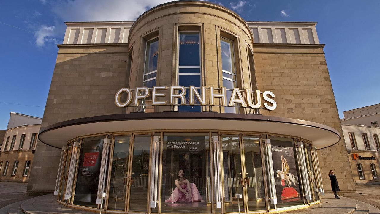 Das Wuppertaler Opernhaus von außen, über den gläsernen Eingangstüren steht in Großbuchstaben "Opernhaus". Das Wuppertaler Opernhaus von außen, über den gläsernen Eingangstüren steht in Großbuchstaben "Opernhaus".