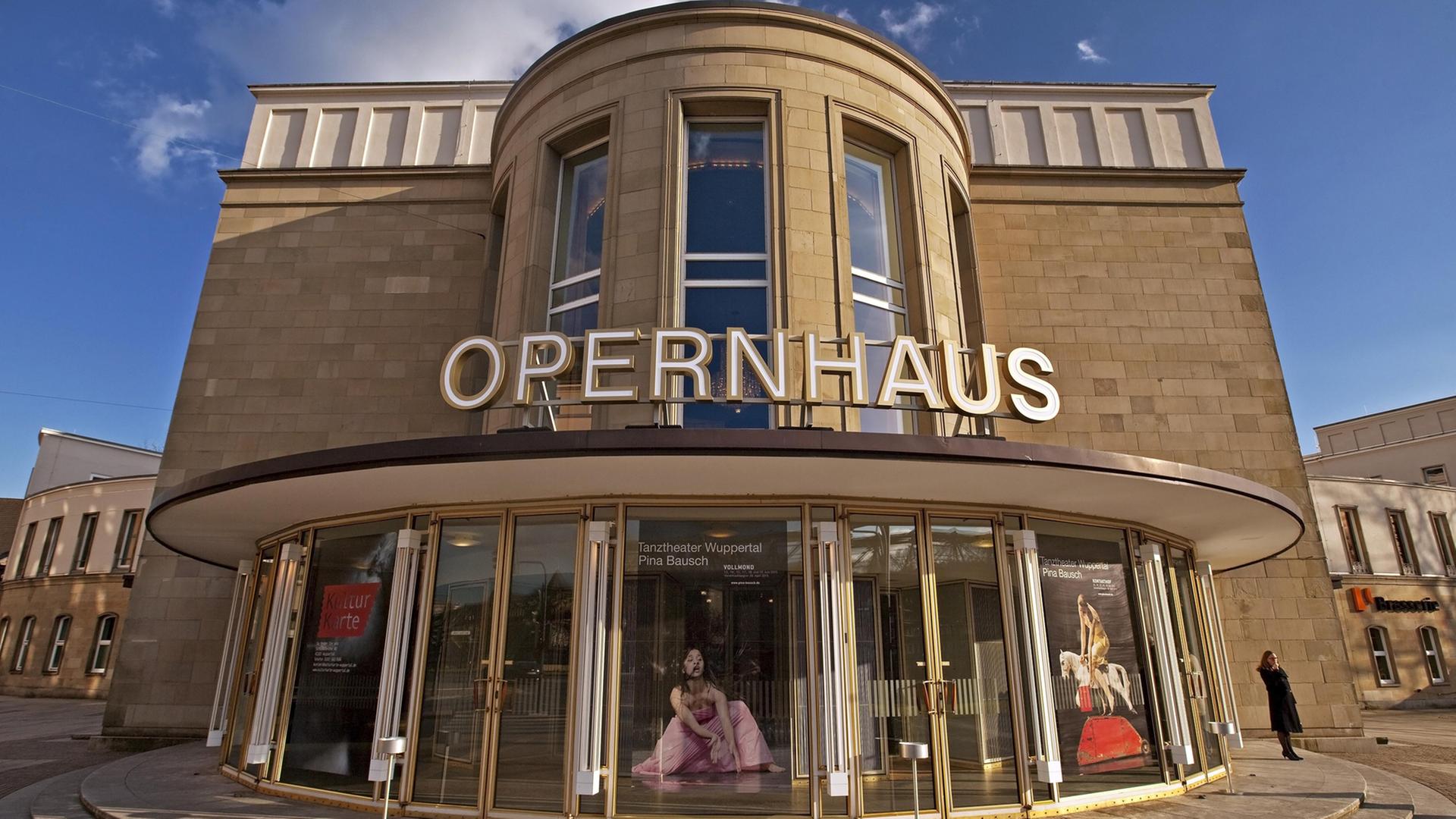 Das Wuppertaler Opernhaus von außen, über den gläsernen Eingangstüren steht in Großbuchstaben "Opernhaus". Das Wuppertaler Opernhaus von außen, über den gläsernen Eingangstüren steht in Großbuchstaben "Opernhaus".