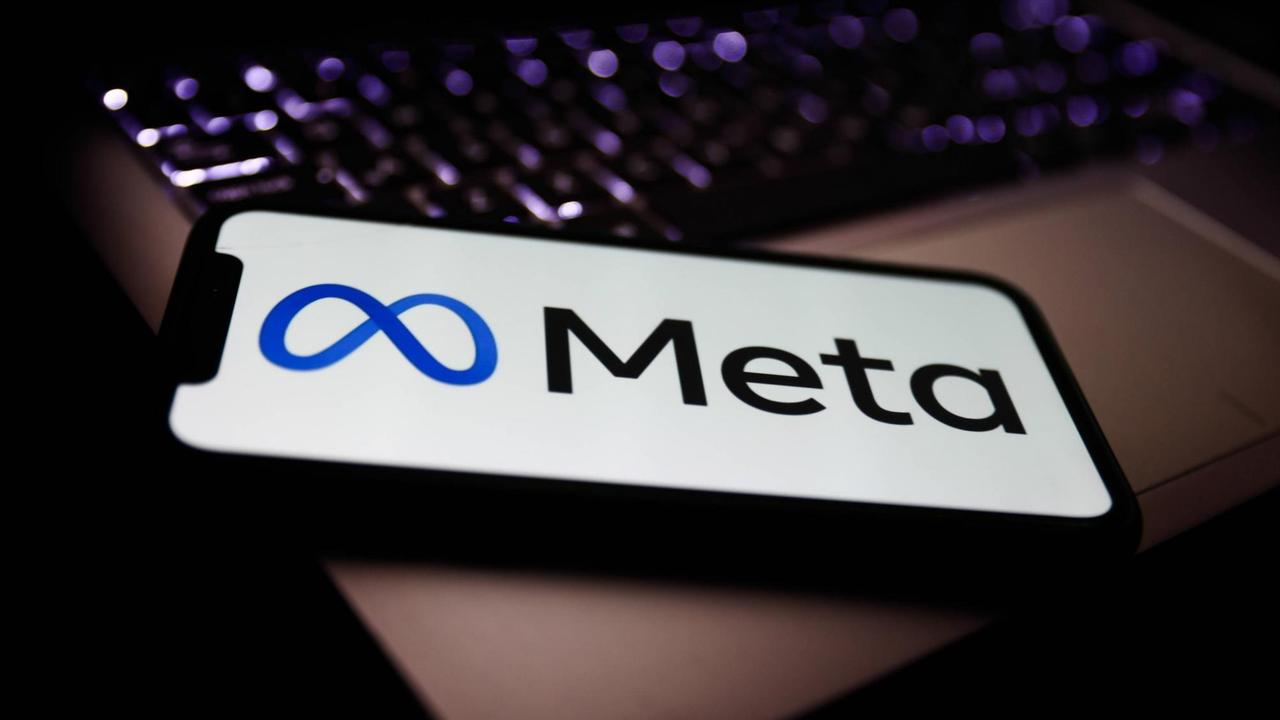 Das neue Logo von Meta (ehemals Facebook) auf einem Smartphone, das auf einem Laptop liegt.