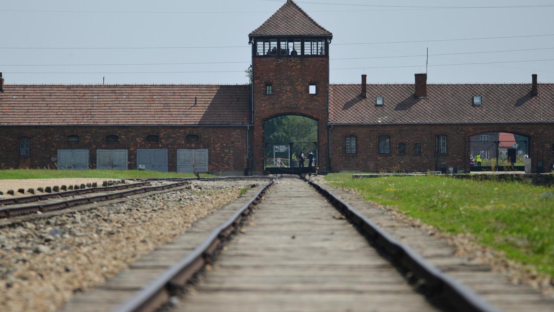 Schienen laufen auf einen Turm des ehemaligen NS-Konzentrationslagers Auschwitz-Birkenau zu. Schienen laufen auf einen Turm des ehemaligen NS-Konzentrationslagers Auschwitz-Birkenau zu.