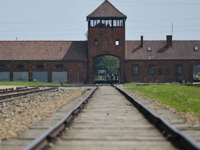 Schienen laufen auf einen Turm des ehemaligen NS-Konzentrationslagers Auschwitz-Birkenau zu.