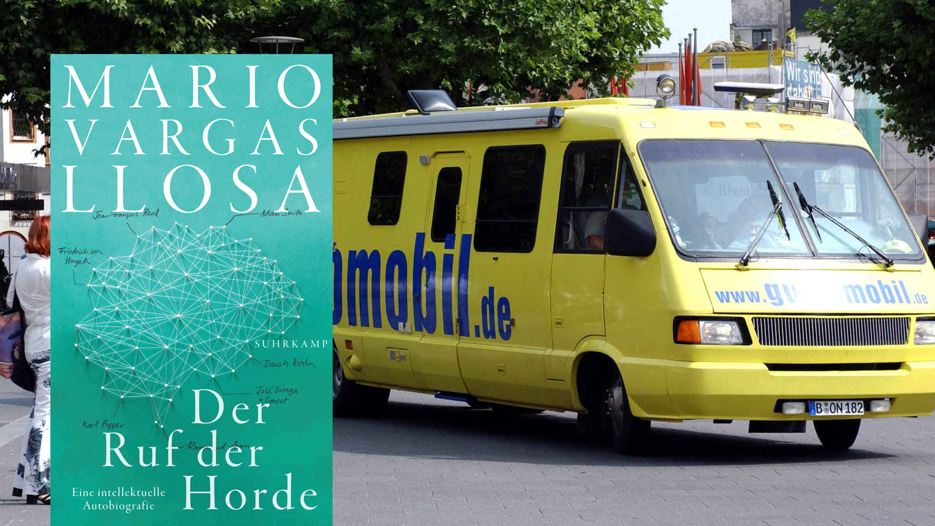 Im Vordergrund ist das Cover des Buches "Der Ruf der Horde". Im Hintergrund ist das sogenannte Guidomobil der FDP, das auf einem Platz steht. Im Vordergrund ist das Cover des Buches "Der Ruf der Horde". Im Hintergrund ist das sogenannte Guidomobil der FDP, das auf einem Platz steht.