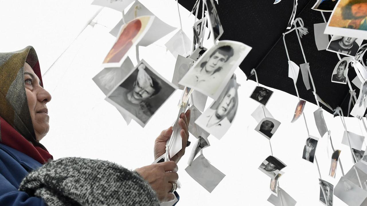 Eine Frau schaut sich die Bilder von Opfern des Balkan-Konflikts an, die vor dem Ort des UNO-Kriegsverbrechertribunals für das frühere Jugoslawien in Den Haag aufgehängt sind Eine Frau schaut sich die Bilder von Opfern des Balkan-Konflikts an, die vor dem Ort des UNO-Kriegsverbrechertribunals für das frühere Jugoslawien in Den Haag aufgehängt sind