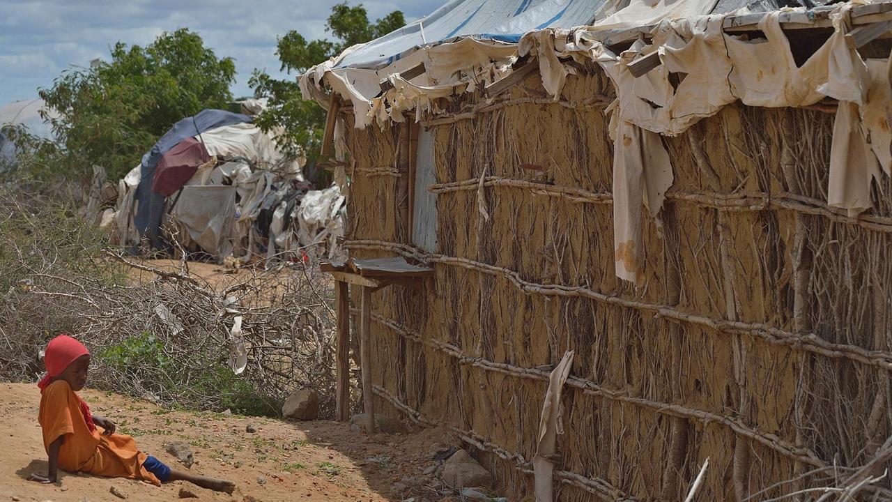 Ein Kind sitzt neben einer bröckelnden Schlammwand im Flüchtlingslager Dadaab in Kenia. Ein Kind sitzt neben einer bröckelnden Schlammwand im Flüchtlingslager Dadaab in Kenia.