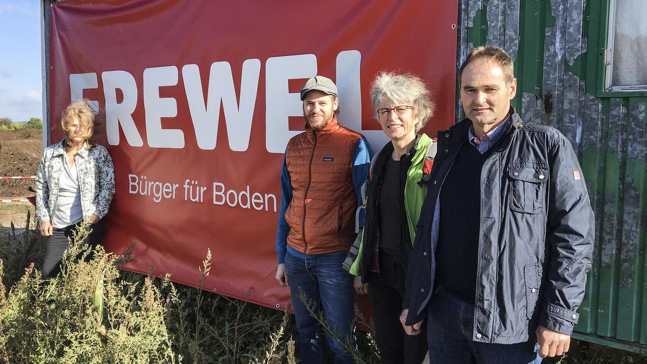 Vor einem Bauwagen auf einem Feld steht eine Gruppe von vier Personen. Der Bauwagen trägt ein Transparent von der "Bürger für Boden Wetterau"- Initiative. Vor einem Bauwagen auf einem Feld steht eine Gruppe von vier Personen. Der Bauwagen trägt ein Transparent von der "Bürger für Boden Wetterau"- Initiative.