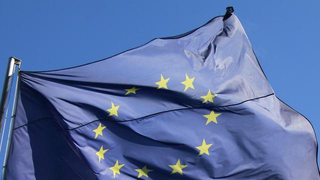 Eine europäische Fahne weht unter blauem Himmel.